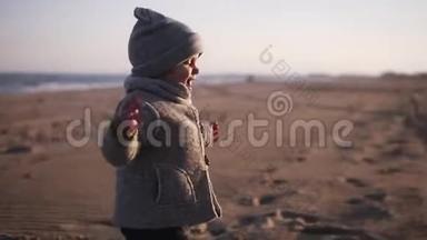 快乐的小幼儿跑到妈妈身边拥抱在秋天的沙滩上.. 可爱的孩子抱着他妈妈，他们摔倒了